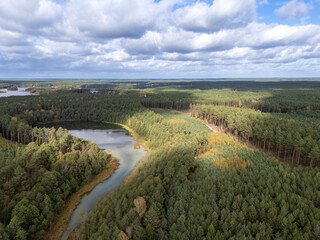 Obraz premium Aerial View of Forested Hills Surrounding Serene Lake with Overcast Sky