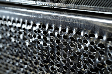Closeup of an aluminum car radiator showcasing the intricate mesh pattern for efficient cooling space for text