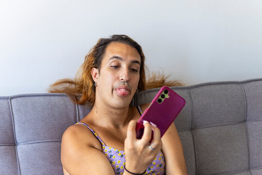 Trans woman lounging on sofa making playful face with phone
