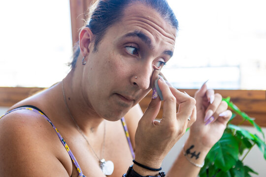 Trans woman applying makeup by a sunny window