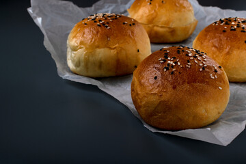 Yeast buns with sesame seeds on a gray background. Homemade bakery product. Copy space