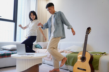 Two young Asian people dancing at home