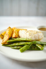 Healthy grilled fish with roasted potatoes and green beans served on a white plate