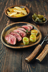 A delicious plate of freshly grilled steak with roasted potatoes and pickles on a wooden table