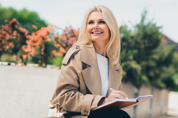 Photo of lovely dreamy woman dressed in stylish clothes enjoying sunny autumn weather day writing...