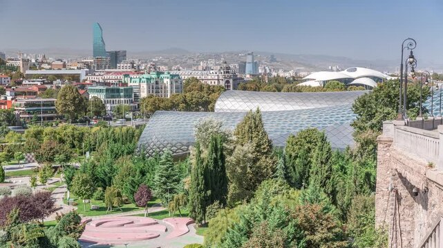 The Musical Theatre and the Exhibition Hall located inside the Rhike Park in Tbilisi aerial timelapse, the capital of Georgia. Houses and skyscrapers on a background
