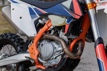 detailled close up of the engine, exhaust, brakes and tyre of a motorcycle dirt bike