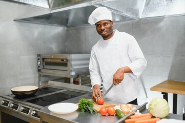 Portrait of happy African American male chef standing in restaurant kitchen