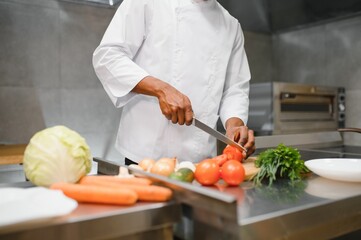 African American chef cooking tasty salad in kitchen