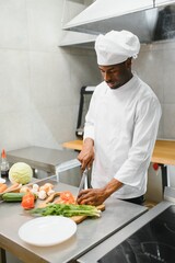 Portrait of happy African American male chef standing in restaurant kitchen