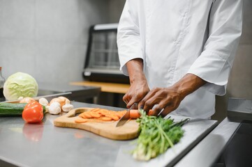 Close up of a afro american man chopping vegetables to make a salad at the kitchen