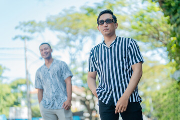 Obraz premium On a sunny day, two young men pose confidently in casual attire, enjoying the moment