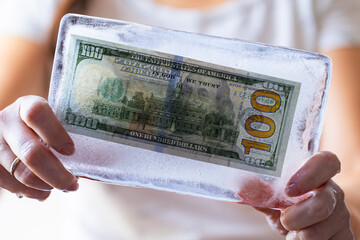 100 US dollar frozen under a layer of ice in hands  for design purpose