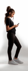 Fototapeta premium Full body side profile of young woman using smartphone against a white background