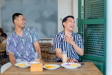Two friends laughing together over breakfast in a bright caf atmosphere