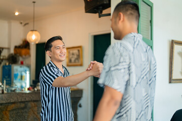 Obraz premium Two men share a friendly handshake in a stylish cafe, fostering connection and camaraderie
