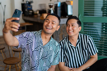 Two friends take a cheerful selfie in stylish shirts, enjoying the happy moment together