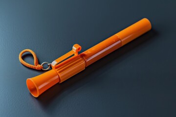 Bright orange whistle resting on a dark surface with a cord for easy carrying