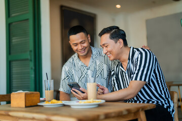 Obraz premium Two friends laughing and sharing a moment over coffee in a cozy caf
