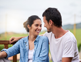 Fototapeta premium Happy couple, relax and love with bonding on bench for date, holiday or outdoor weekend in countryside. Young, man and woman with smile in joy for romance, relationship or morning together on porch