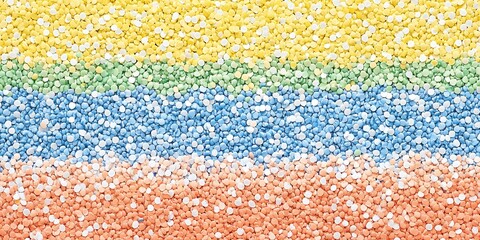 A close-up shot of colorful sprinkles arranged in horizontal stripes. The colors are yellow, green, blue, and peach.