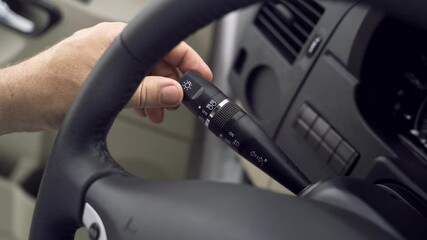 The driver showcases how to operate the vehicle's external lighting switch. Side lights, high beams, and low beams are turned on and off to highlight their functions.