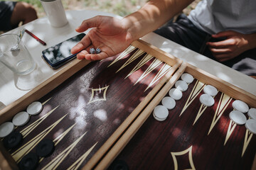 A detailed view of a backgammon board game in progress with dice and player interaction under natural light, creating a relaxed atmosphere.