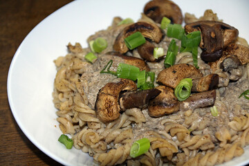 Italian pasta with mushrooms, cream sauce made from mushrooms and spring onions, served on a white plate