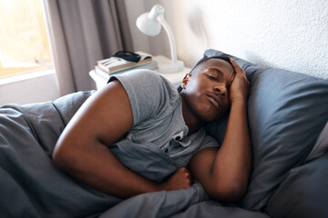 Obraz premium Sleeping, tired and black man in bed for morning for resting, dreaming and nap in home. House, bedroom and African person comfortable with duvet, pillow and blanket for relaxing on bed on weekend