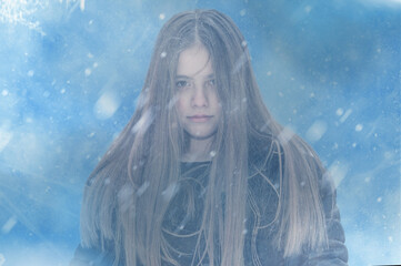 Frozen girl shivering from cold on blue snowy background.