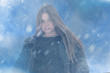 Frozen girl shivering from cold on blue snowy background.