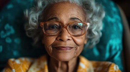 A close-up of an elderly woman with curly gray hair, wearing vintage eyeglasses, emanating warmth and wisdom, seated against a teal background.