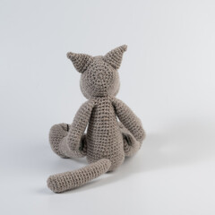 Amigurumi doll wolf gray sits there white isolated
