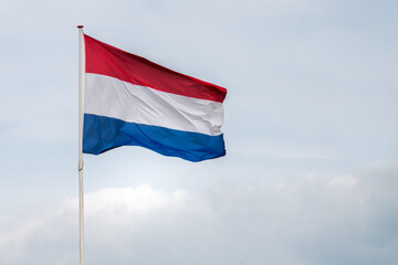 The flag of the Netherlands fluttering in the wind. Red, White and Blue. National pride and unity. The spirit of patriotism in Holland. Sky, water or buildings in the background.