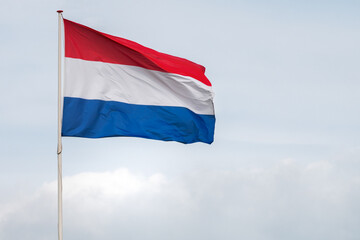 The flag of the Netherlands fluttering in the wind. Red, White and Blue. National pride and unity. The spirit of patriotism in Holland. Sky, water or buildings in the background.