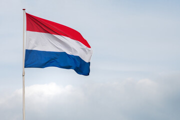 The flag of the Netherlands fluttering in the wind. Red, White and Blue. National pride and unity. The spirit of patriotism in Holland. Sky, water or buildings in the background.