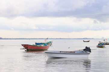 Fototapeta premium A serene seascape with several small fishing boats anchored in shallow waters. 