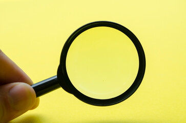 Hand holding magnifying with yellow background and with customizable space for text or ideas