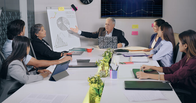 Indian happy old aged boss ceo man male show growth chart market graph stock data look TV screen share good ideas plan young adult expert girl team older lady intern staff group job office work place