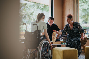 A boy with Down syndrome, a girl in a wheelchair, and an elderly woman enjoy a building blocks...