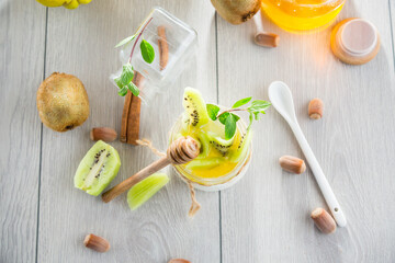 Homemade yogurt in a glass jar with honey, kiwi, nuts.