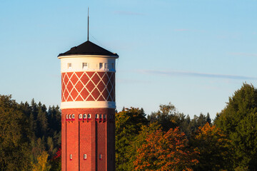 Brick tower in the morning of autumn in Finland against a clear sky and colorful forest