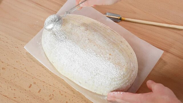 Homemade bread. Hands of a girl on a bread blank with a special knife makes a pattern of a spike and a cut. Close-up, top view. Sourdough bread, bake, molding, bread on the table, baking, bake