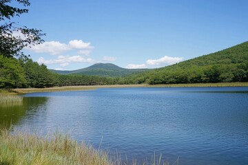 Obraz premium Tranquil lake reflecting mountains under a bright blue sky in the early afternoon