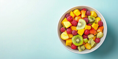 Vibrant fruit salad in a white bowl against a light blue background, highlighting colorful ingredients like kiwi, mango, and raspberries.