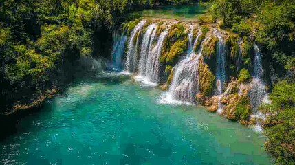 Fototapeta premium Drone view of a waterfall cascading into a clear blue river.
