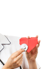 Obraz premium Hand of doctor with stethoscope examining red heart made of paper. Health care and treatment. Copy spece for text