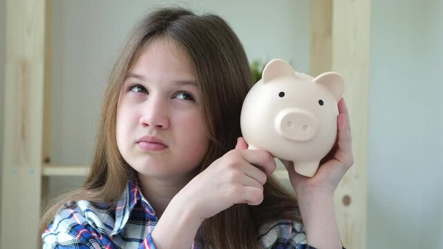 Sad preteen girl holding piggy bank and thinking. Financial problems, economy, savings and expenses concept