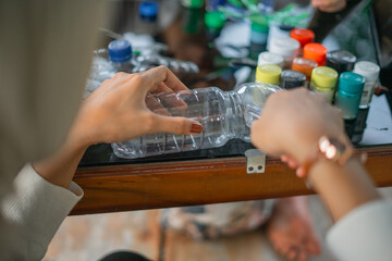 crop view female hand cutting plastic bottle waste using cutter