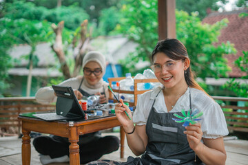 asian female making plastic bottle waste handcraft with friend